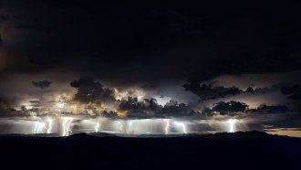 Thunderstorms hover over Lake Maracaibo at night. Lightning bolts flash from eerily lit clouds.
