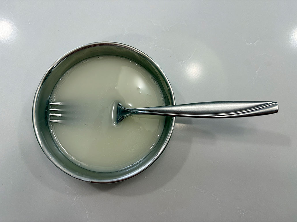 a bowl of milky white liquid with a fork in it