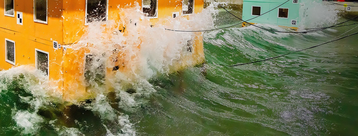 Scale-model buildings are subjected to simulated waves to test how the structures react to water forces. 