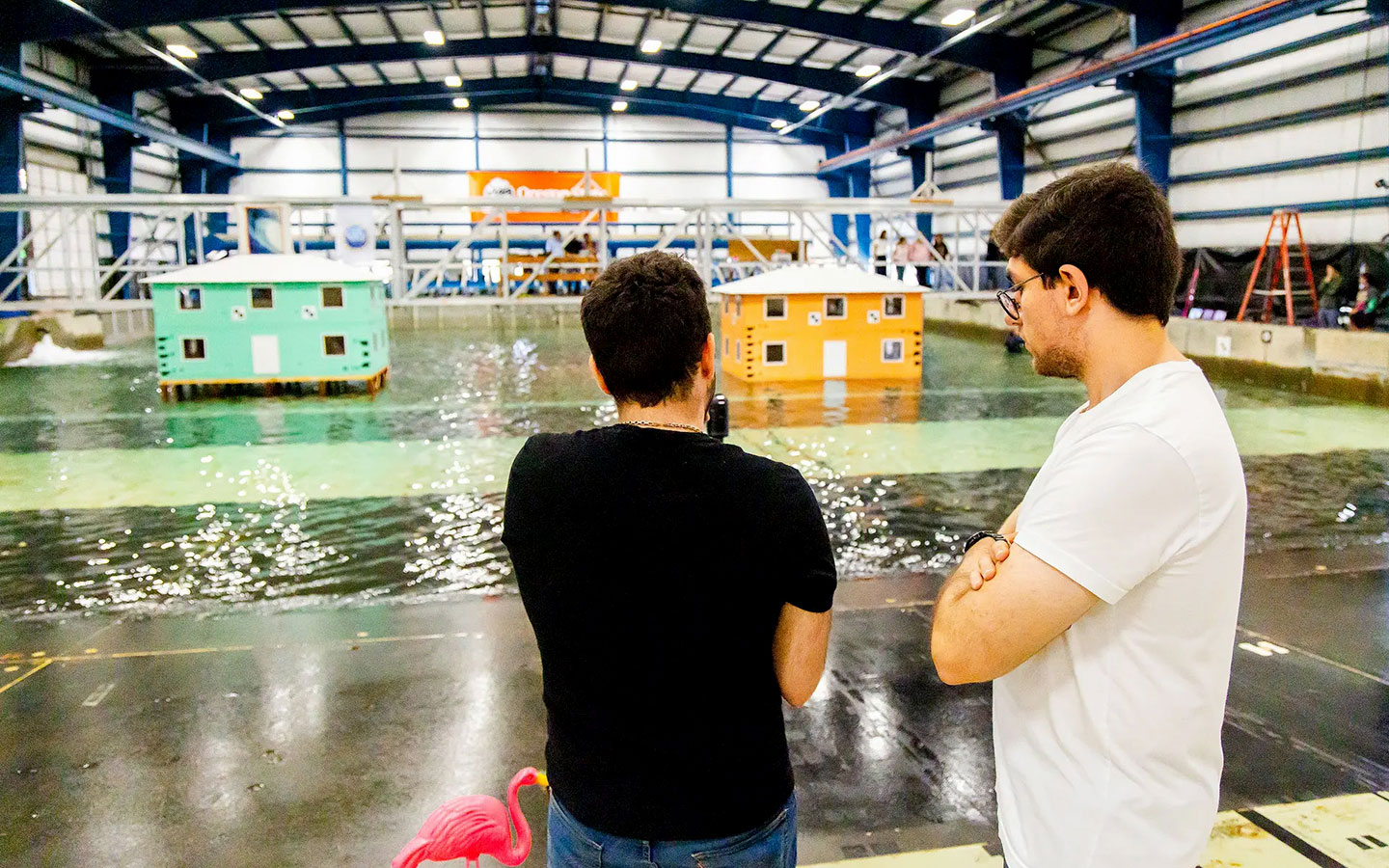 Two researchers looking at the wave machine and scale building models at their lab