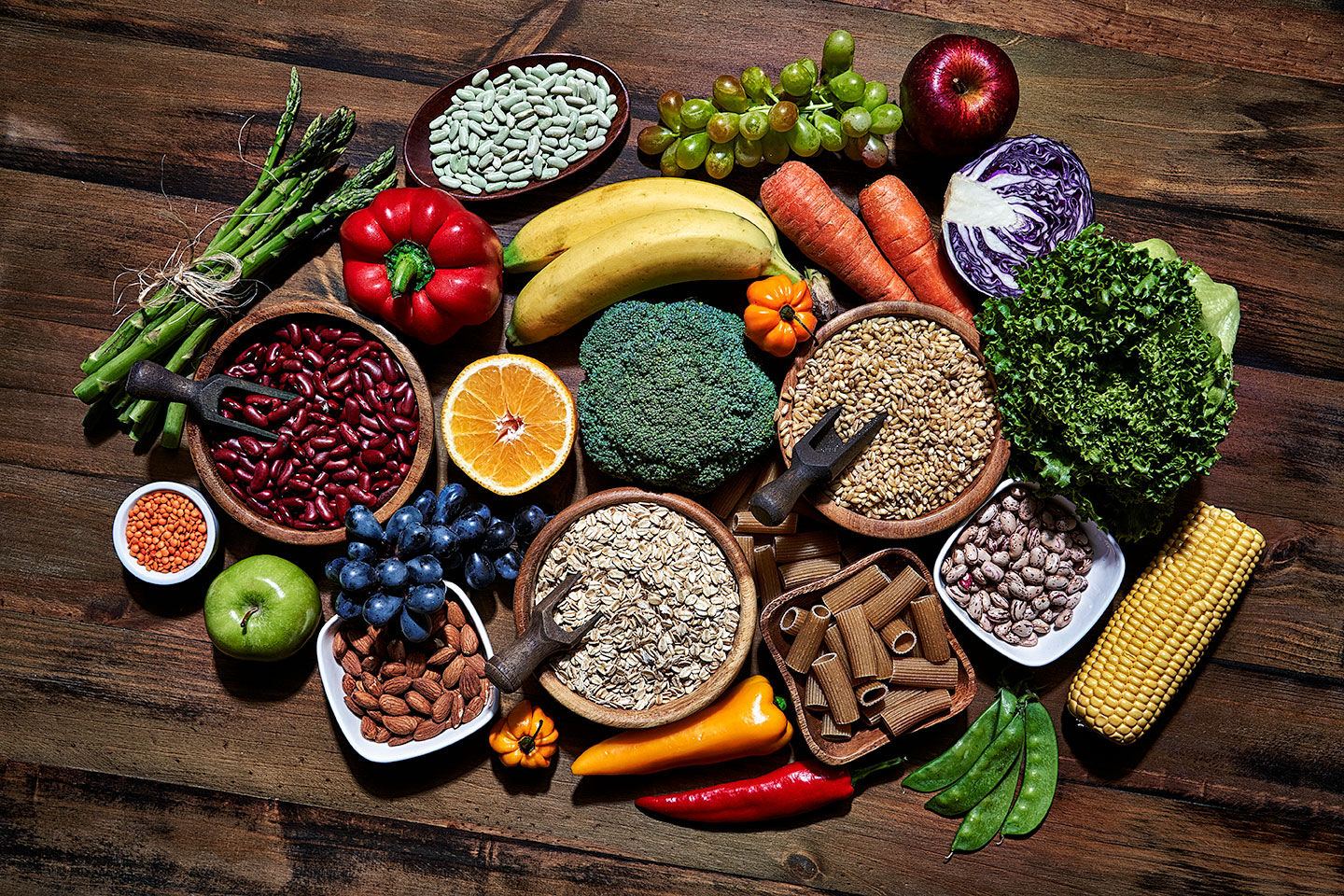 a selection of whole foods, fruit, vegetable, beans, whole grains arranged on a table