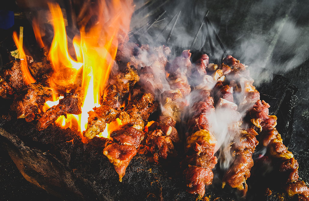 meat kebabs cook on an open flame