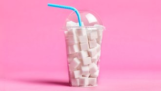 a clear plastic drink cup with a domed lid full of sugar cubes, there is a blue straw going into the cup